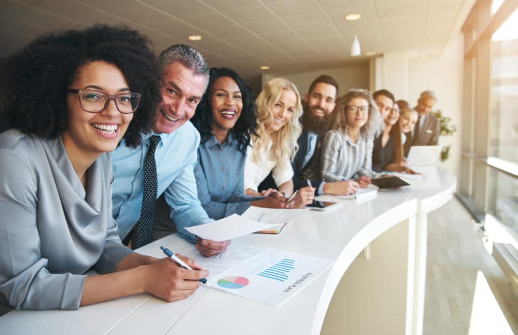 Cheerful diverse and multigenerational employees smiling at camera in office