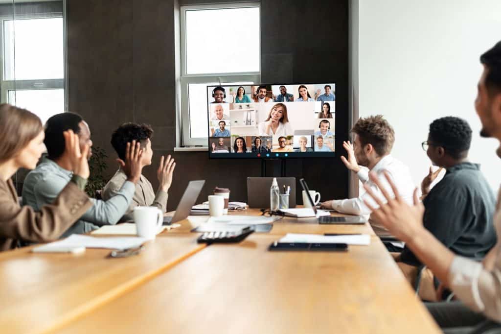 Hybrid Workplace with diverse employees in office making video call to remote employees