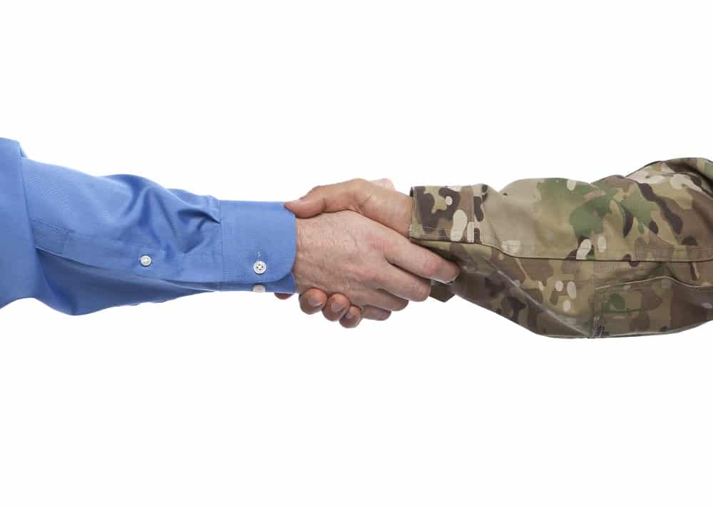 Businessman shaking US army soldiers hand at a job interview that hires veterans